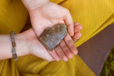 Photo of Woman meditating with crystal to heal or restore her aura outdoors, closeup