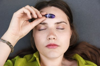 Photo of Woman meditating with crystal to heal or restore her aura on mat, above view