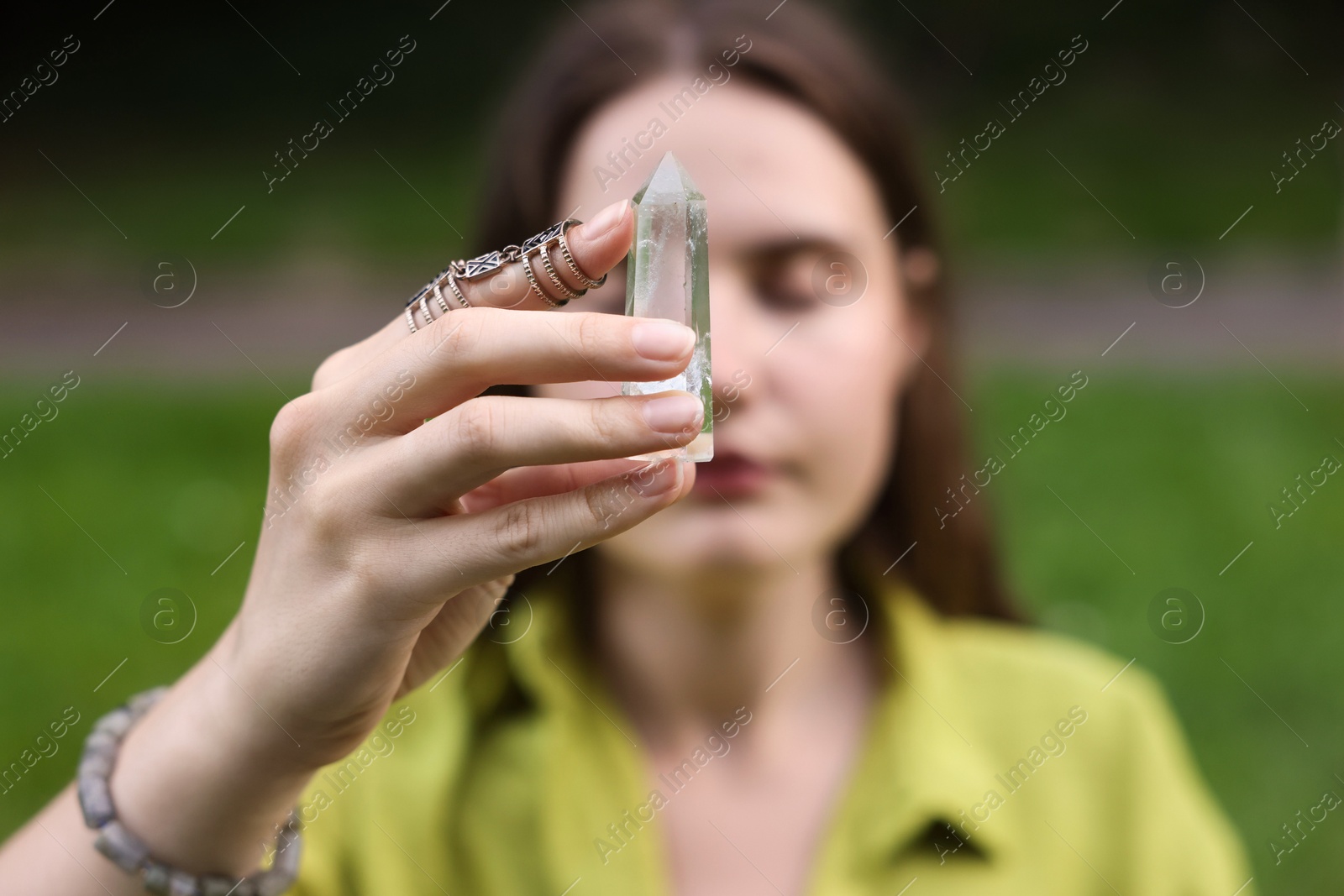 Photo of Woman meditating with crystal to heal or restore her aura outdoors, selective focus