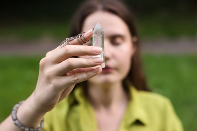 Photo of Woman meditating with crystal to heal or restore her aura outdoors, selective focus