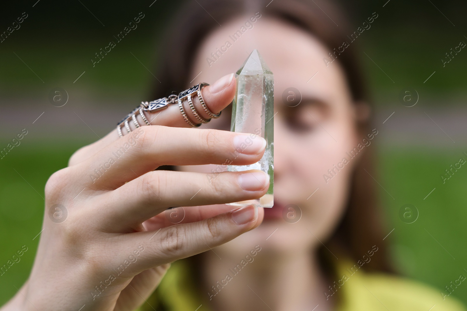Photo of Woman meditating with crystal to heal or restore her aura outdoors, selective focus