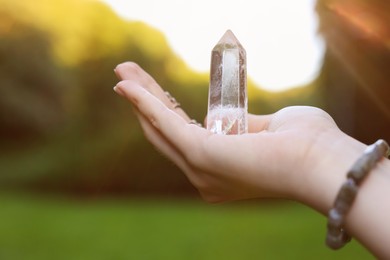 Photo of Woman meditating with crystal to heal or restore her aura outdoors, closeup