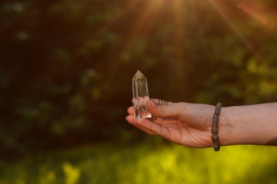 Photo of Woman meditating with crystal to heal or restore her aura outdoors, closeup