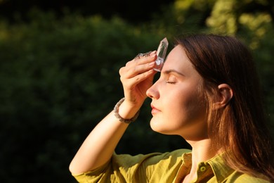 Photo of Woman meditating with crystal to heal or restore her aura outdoors