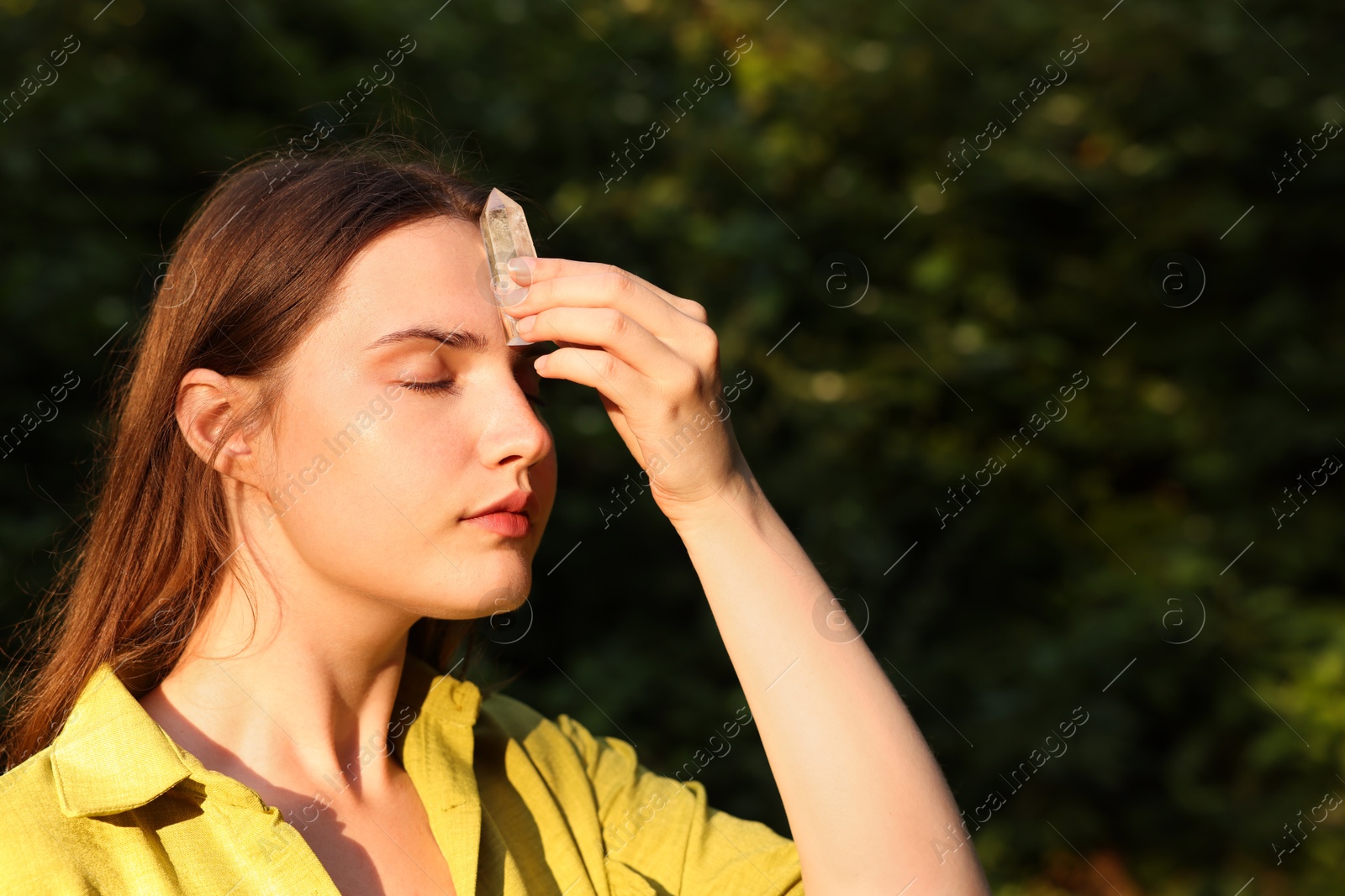 Photo of Woman meditating with crystal to heal or restore her aura outdoors