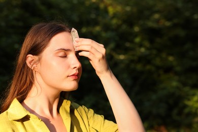 Photo of Woman meditating with crystal to heal or restore her aura outdoors