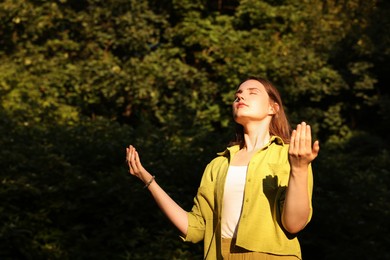 Photo of Woman meditating to heal or restore her aura in nature, space for text