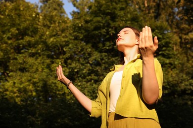 Photo of Woman meditating to heal or restore her aura in nature, space for text