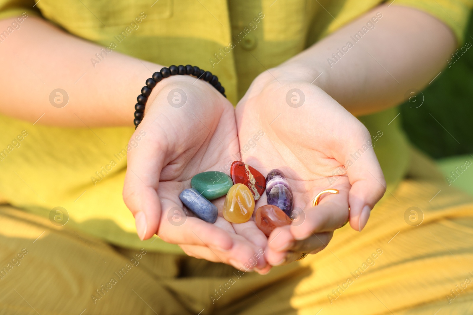 Photo of Woman meditating with crystals to heal or restore her aura outdoors, closeup