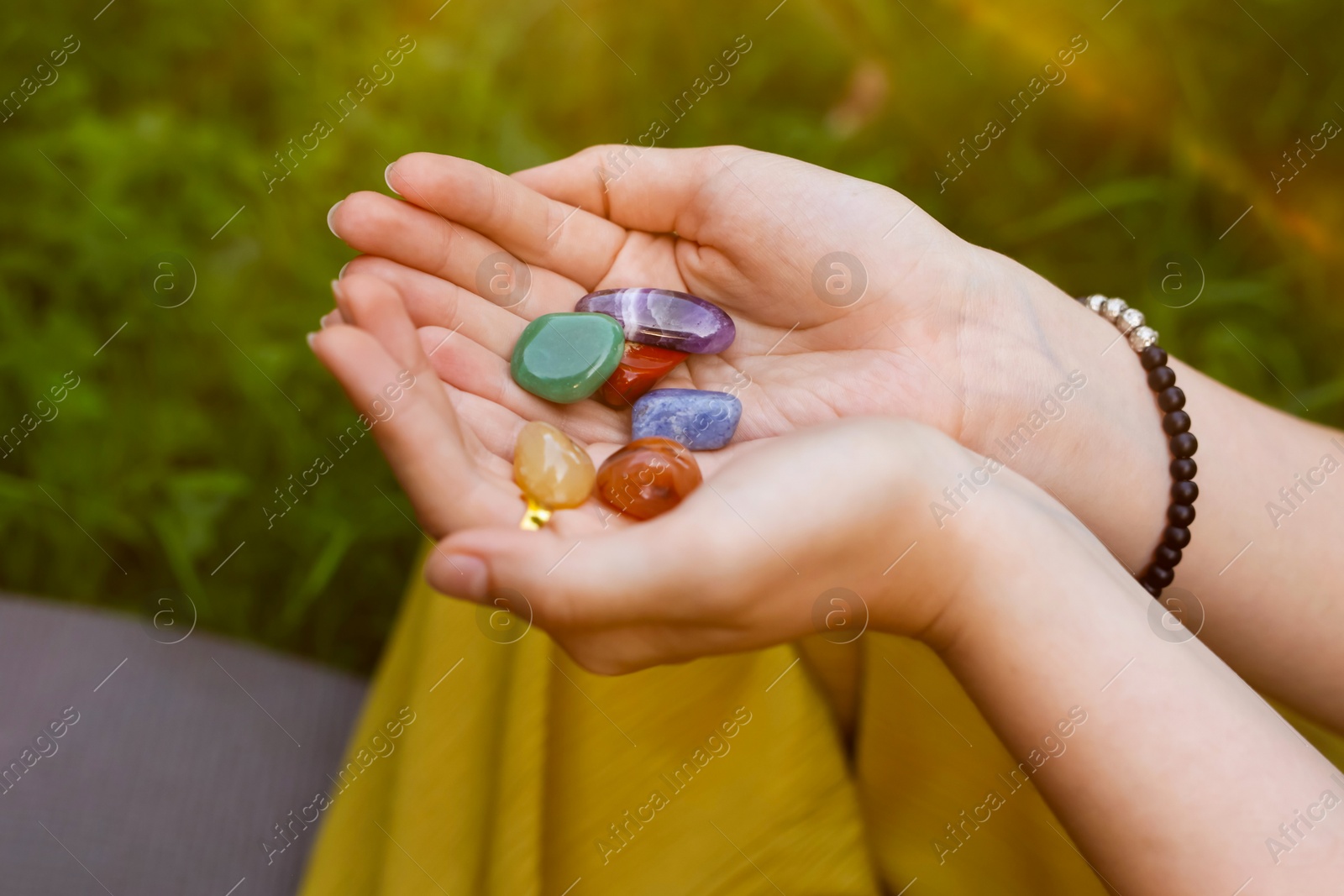 Photo of Woman meditating with crystals to heal or restore her aura outdoors, closeup