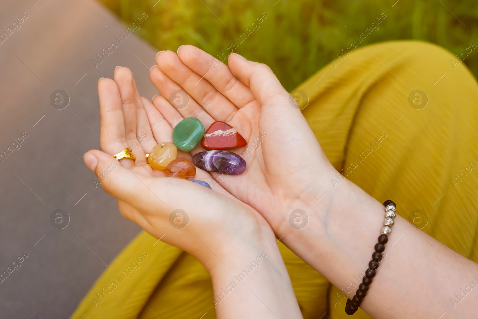 Photo of Woman meditating with crystals to heal or restore her aura outdoors, closeup
