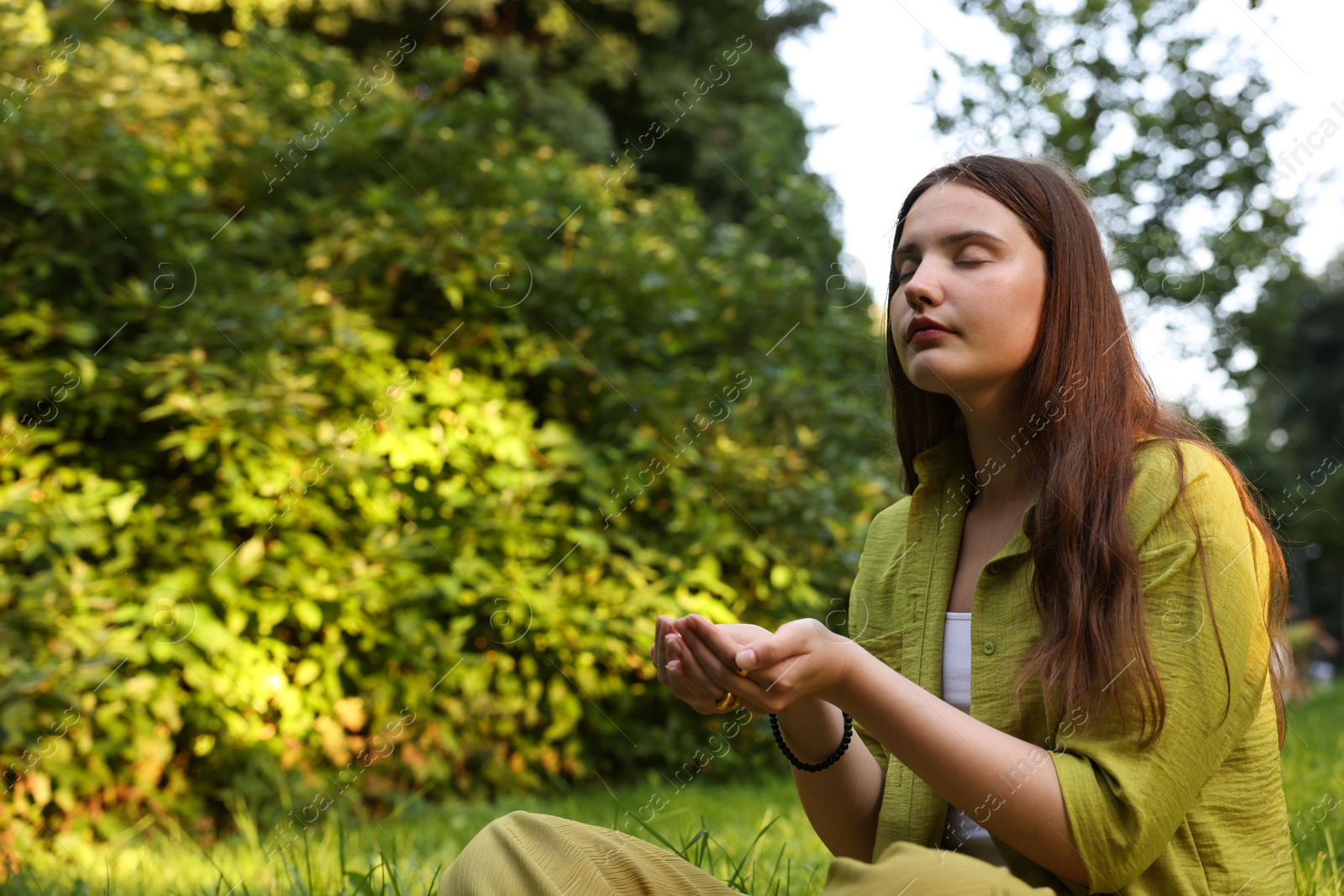 Photo of Woman meditating to heal or restore her aura in nature, space for text