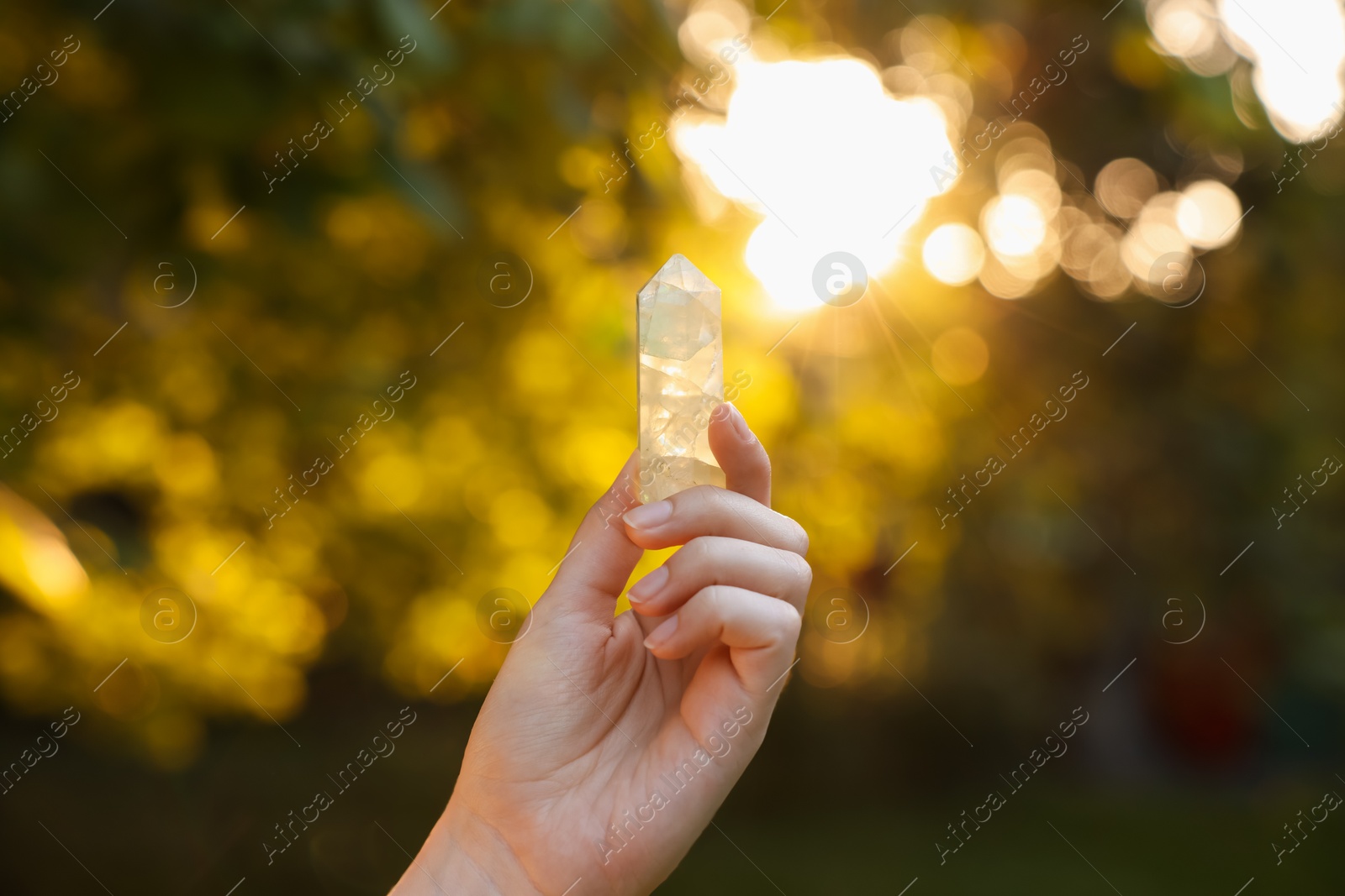 Photo of Woman meditating with crystal to heal or restore her aura outdoors, closeup