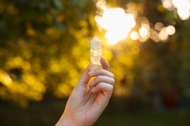Photo of Woman meditating with crystal to heal or restore her aura outdoors, closeup