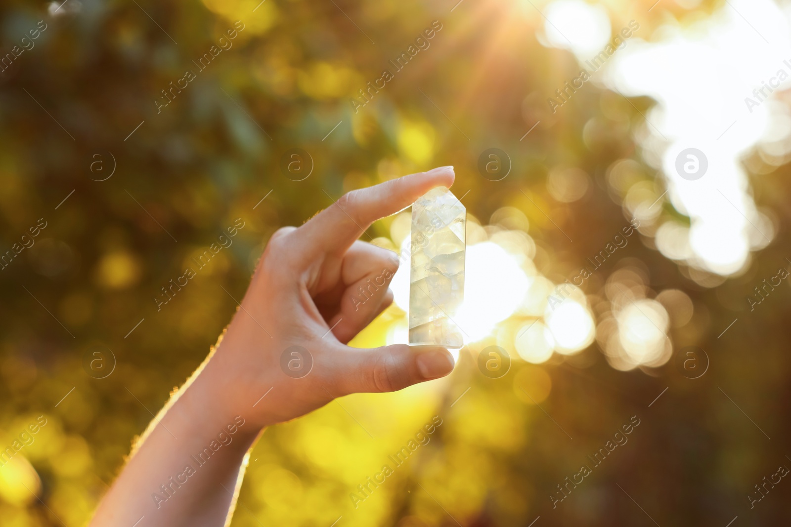 Photo of Woman meditating with crystal to heal or restore her aura outdoors, closeup