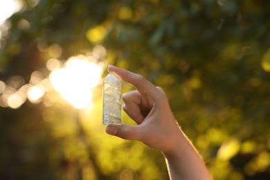 Photo of Woman meditating with crystal to heal or restore her aura outdoors, closeup