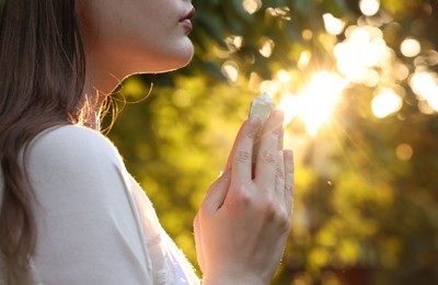 Photo of Woman meditating with crystal to heal or restore her aura outdoors, closeup