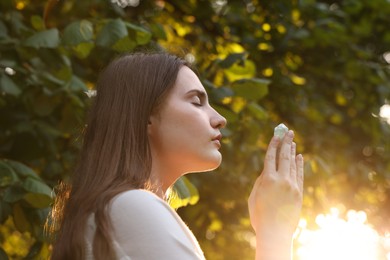 Photo of Woman meditating with crystal to heal or restore her aura outdoors