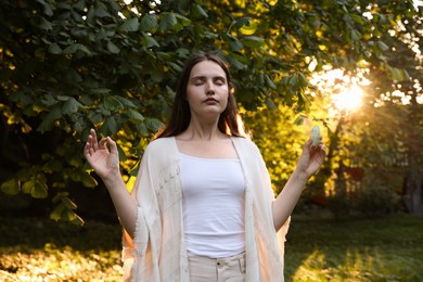 Photo of Woman meditating with crystal to heal or restore her aura outdoors