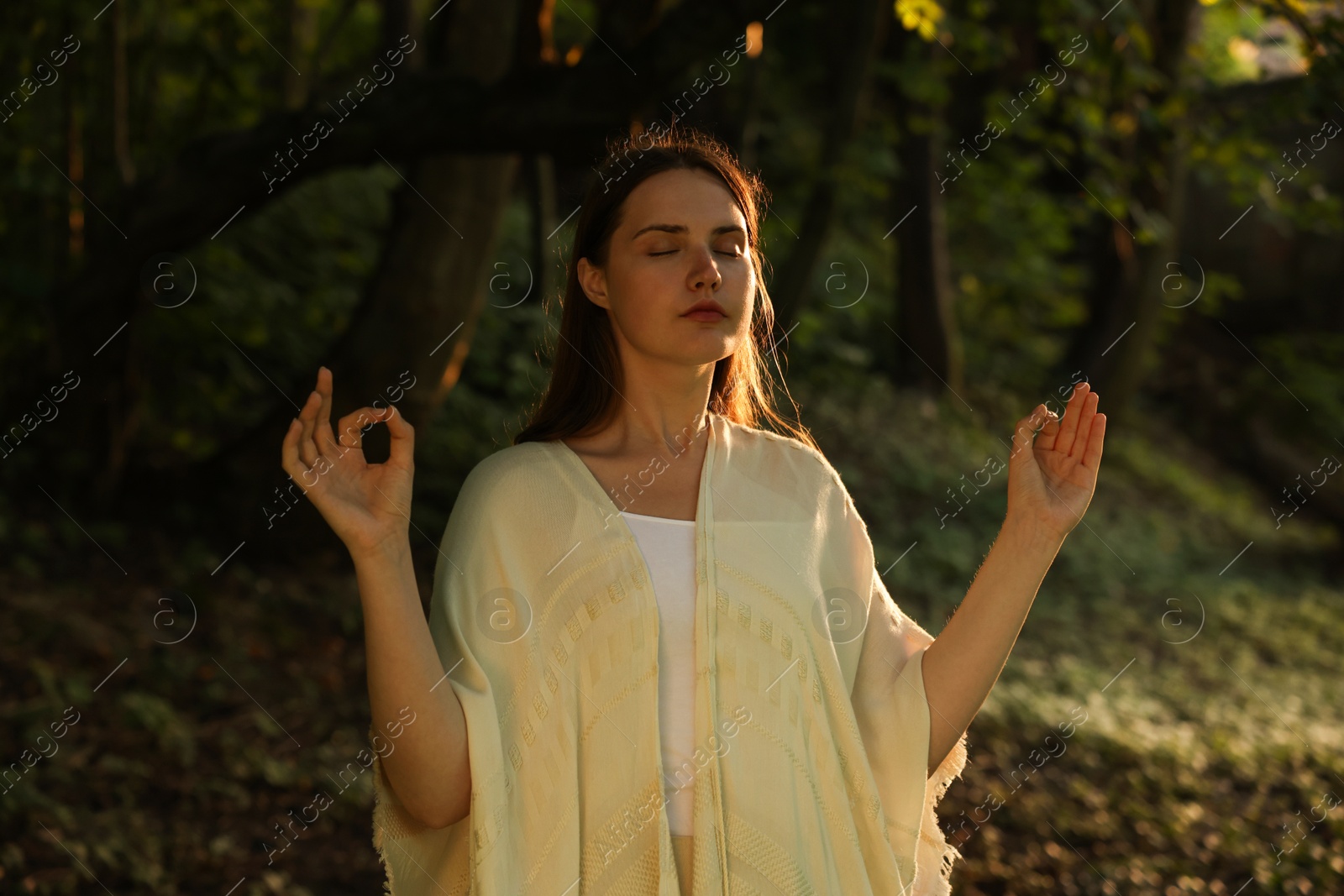 Woman meditating to heal or restore her aura in nature Photo of Woman meditating to heal or restore her aura in nature
