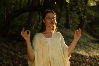 Photo of Woman meditating to heal or restore her aura in nature