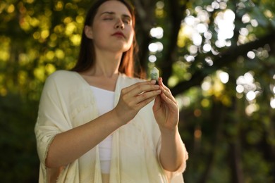 Photo of Woman meditating with crystal to heal or restore her aura outdoors, selective focus