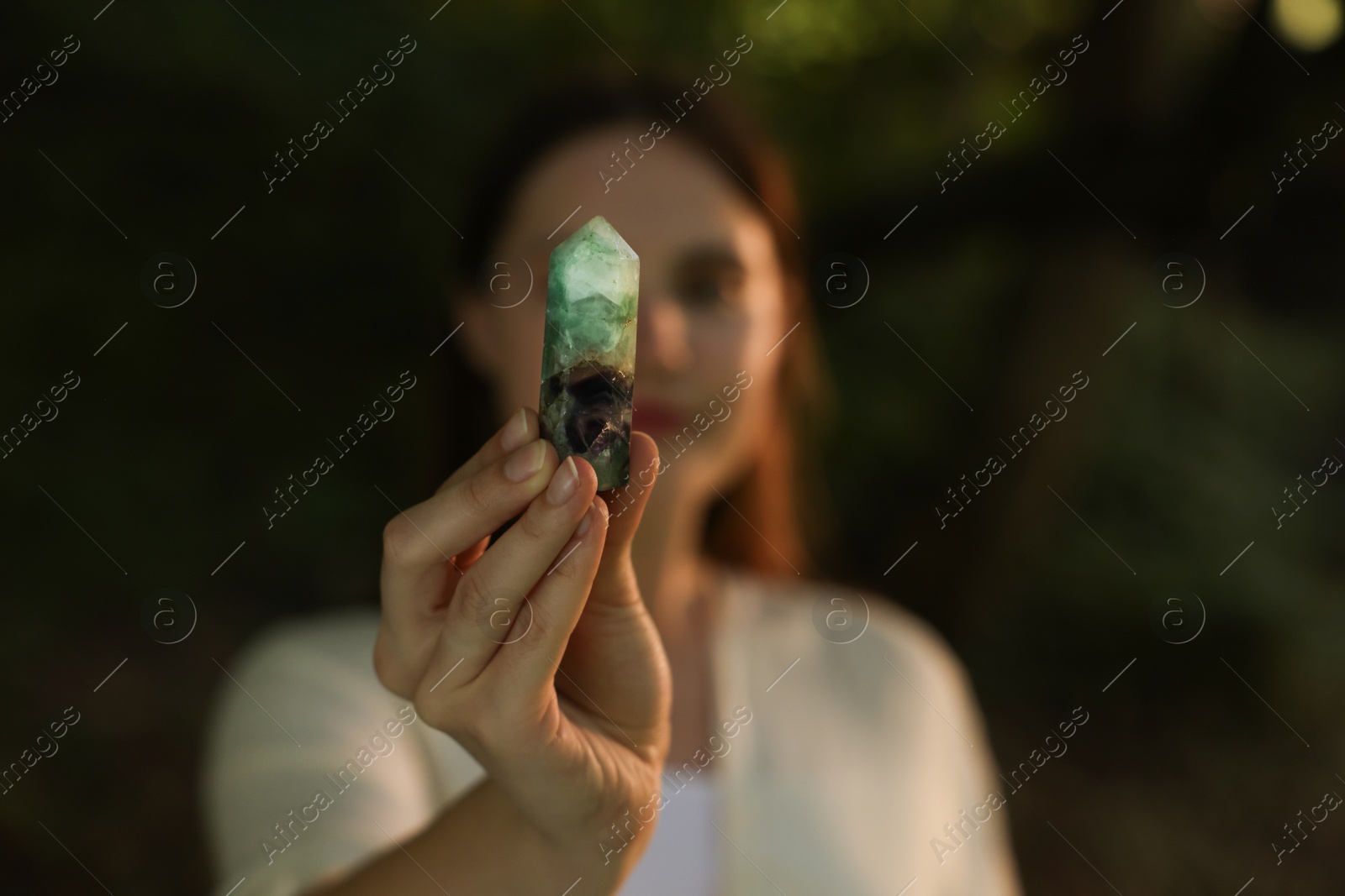 Photo of Woman meditating with crystal to heal or restore her aura outdoors, selective focus