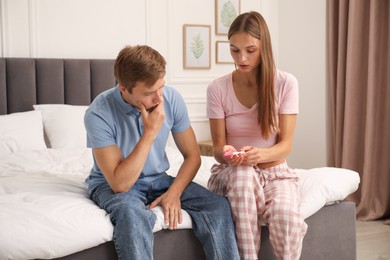 Photo of Worried couple with pregnancy test on bed at home