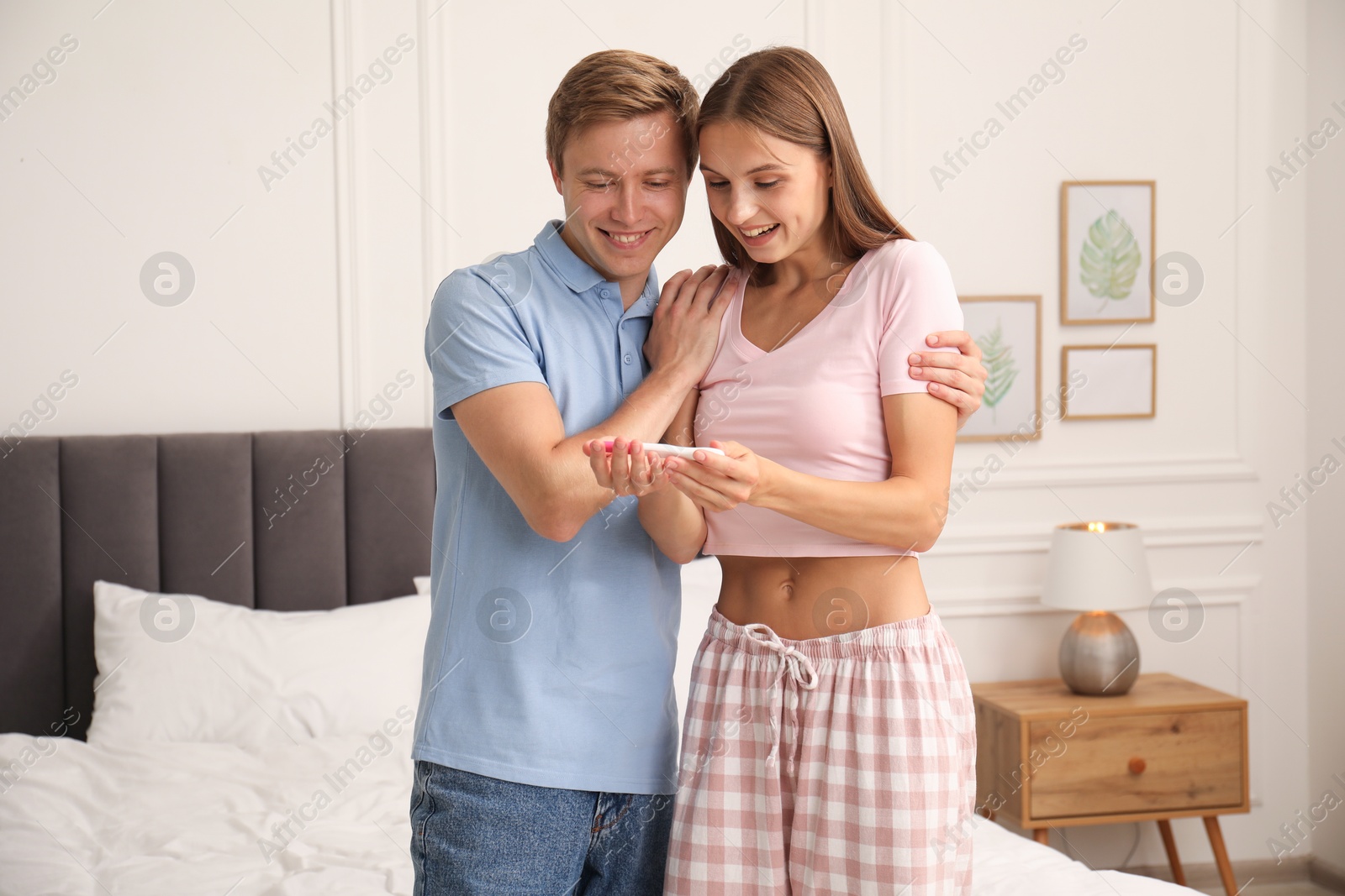 Photo of Happy couple with pregnancy test in bedroom