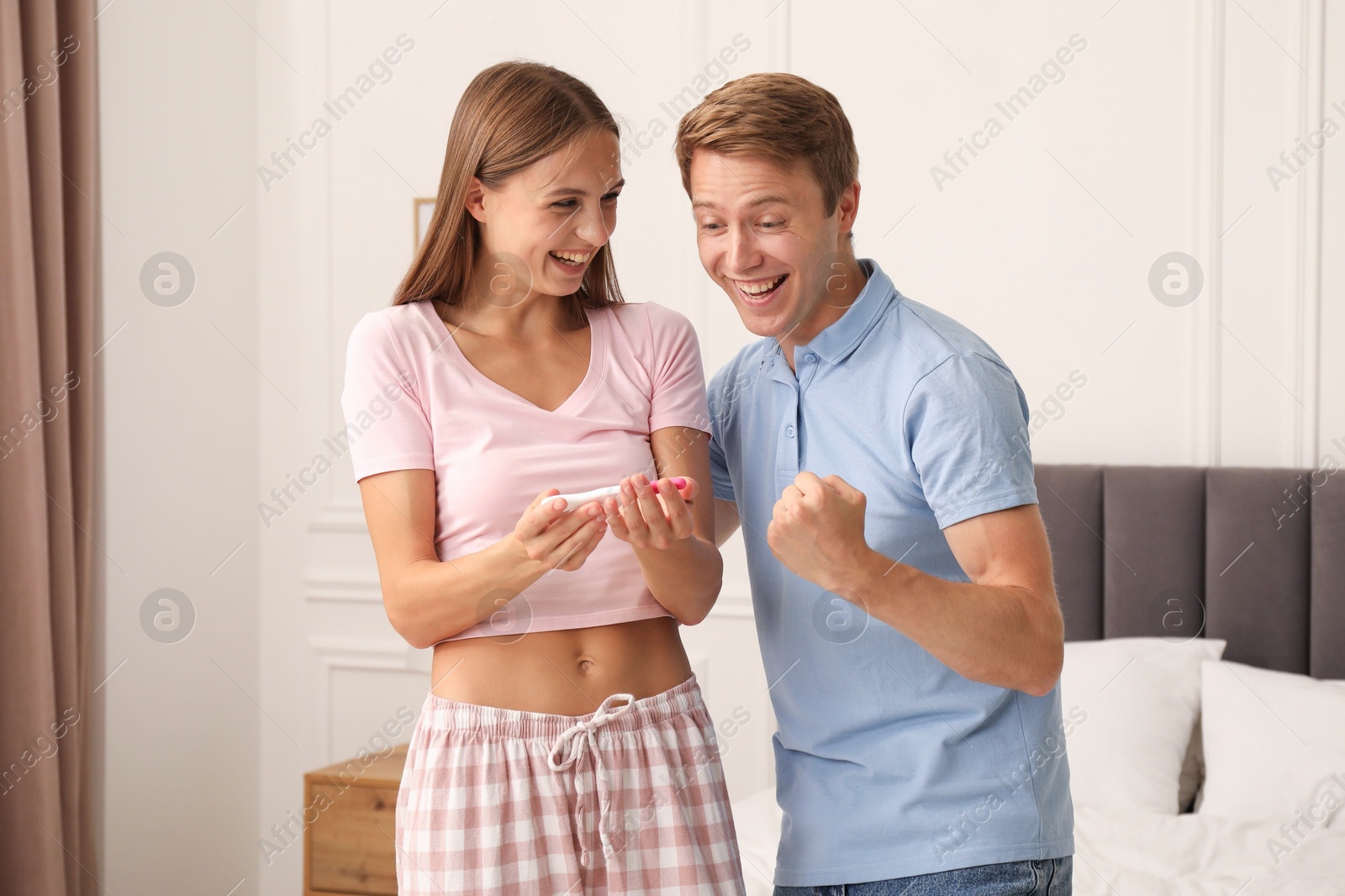 Photo of Happy couple with pregnancy test in bedroom