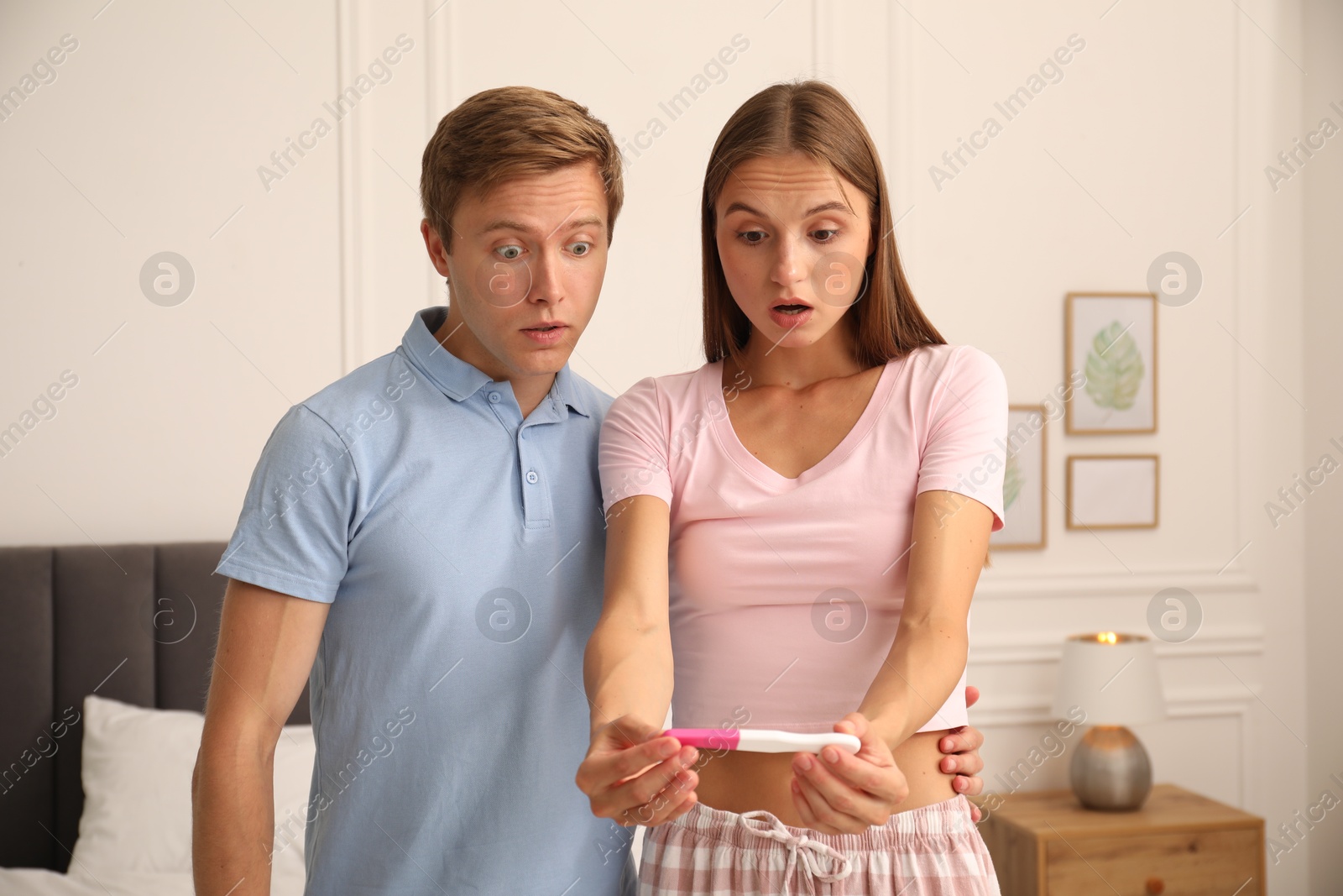 Photo of Emotional couple with pregnancy test in bedroom