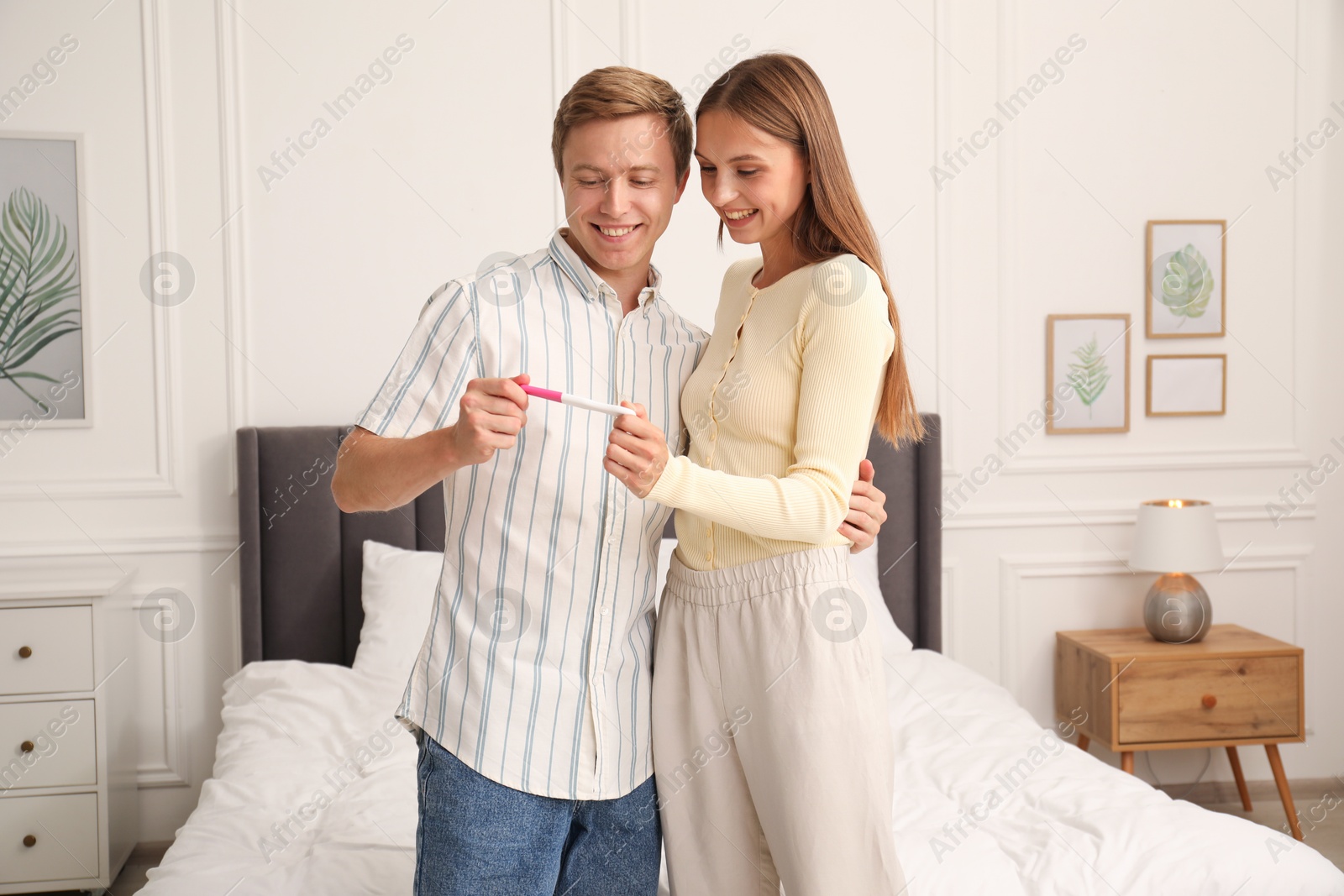 Photo of Happy couple with pregnancy test in bedroom