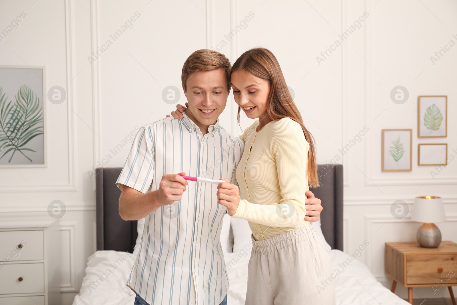 Photo of Happy couple with pregnancy test in bedroom