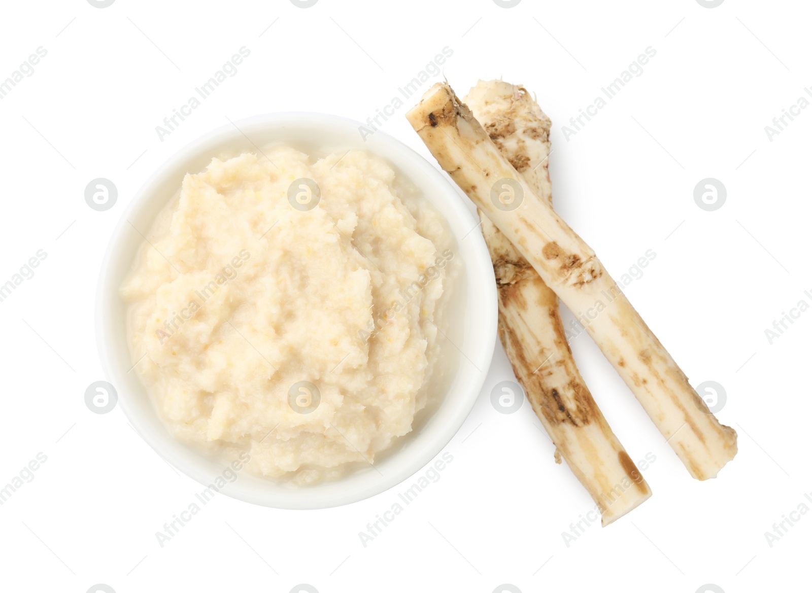 Photo of Tasty horseradish sauce in bowl and roots isolated on white, top view