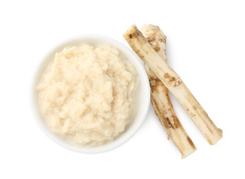 Photo of Tasty horseradish sauce in bowl and roots isolated on white, top view