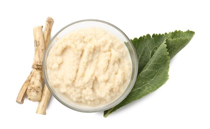 Photo of Tasty horseradish sauce in bowl, roots and leaf isolated on white, top view