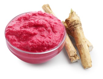 Photo of Tasty horseradish sauce with beetroot in bowl and roots isolated on white