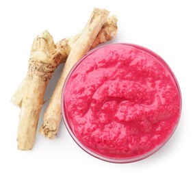 Photo of Tasty horseradish sauce with beetroot in bowl and roots isolated on white, top view