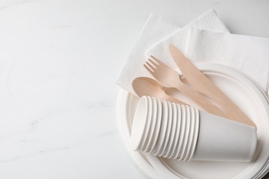 Photo of Set of disposable tableware on white background, top view. Space for text