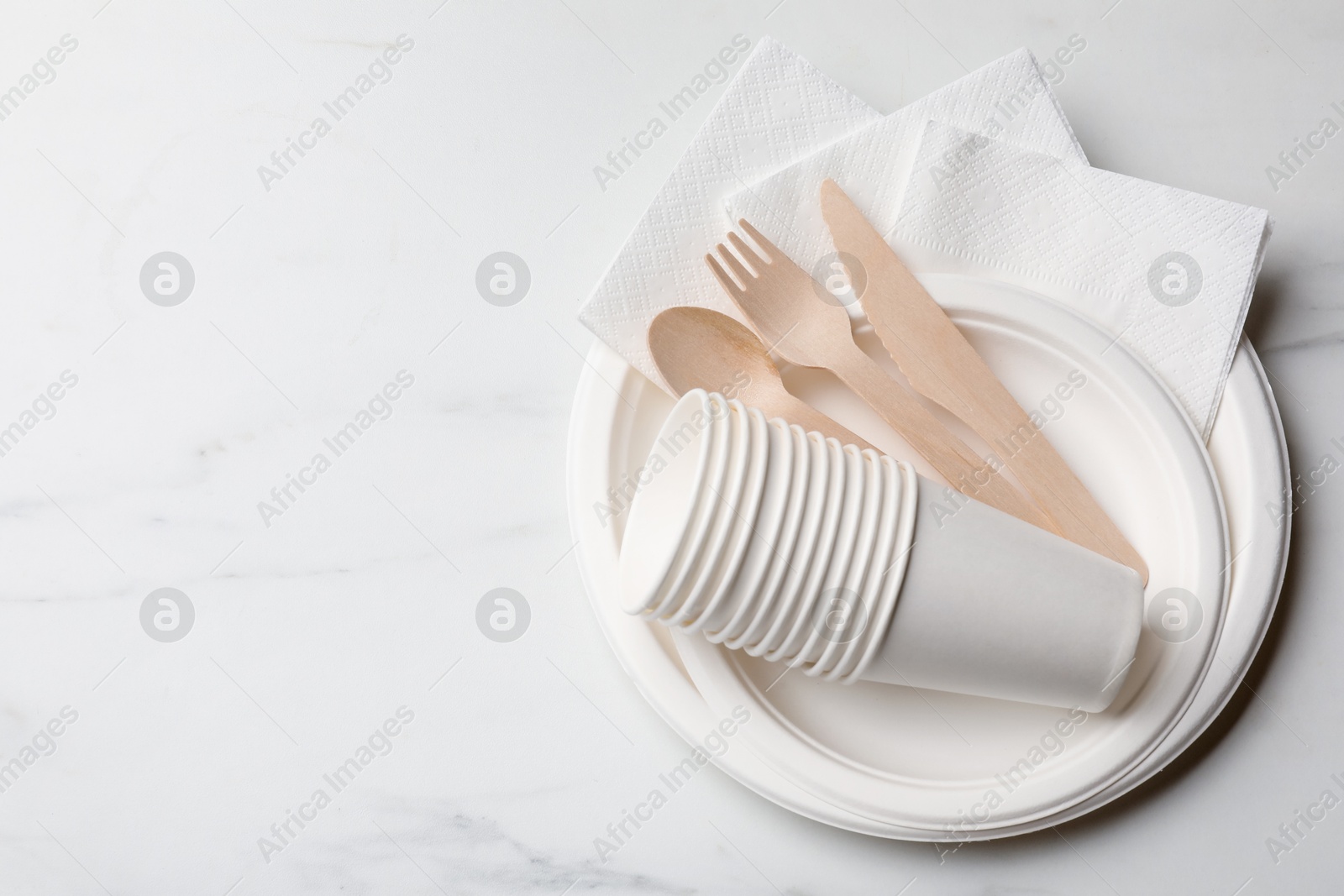 Photo of Set of disposable tableware on white background, top view. Space for text