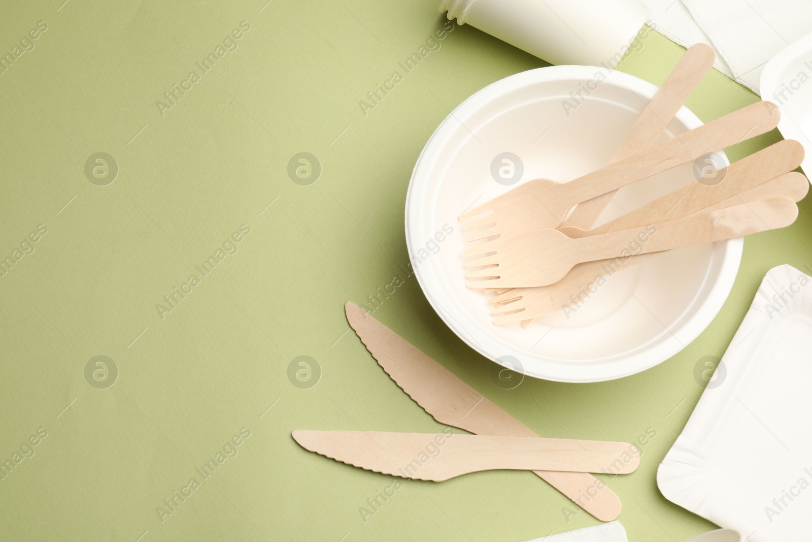 Photo of Set of disposable tableware on olive background, flat lay. Space for text