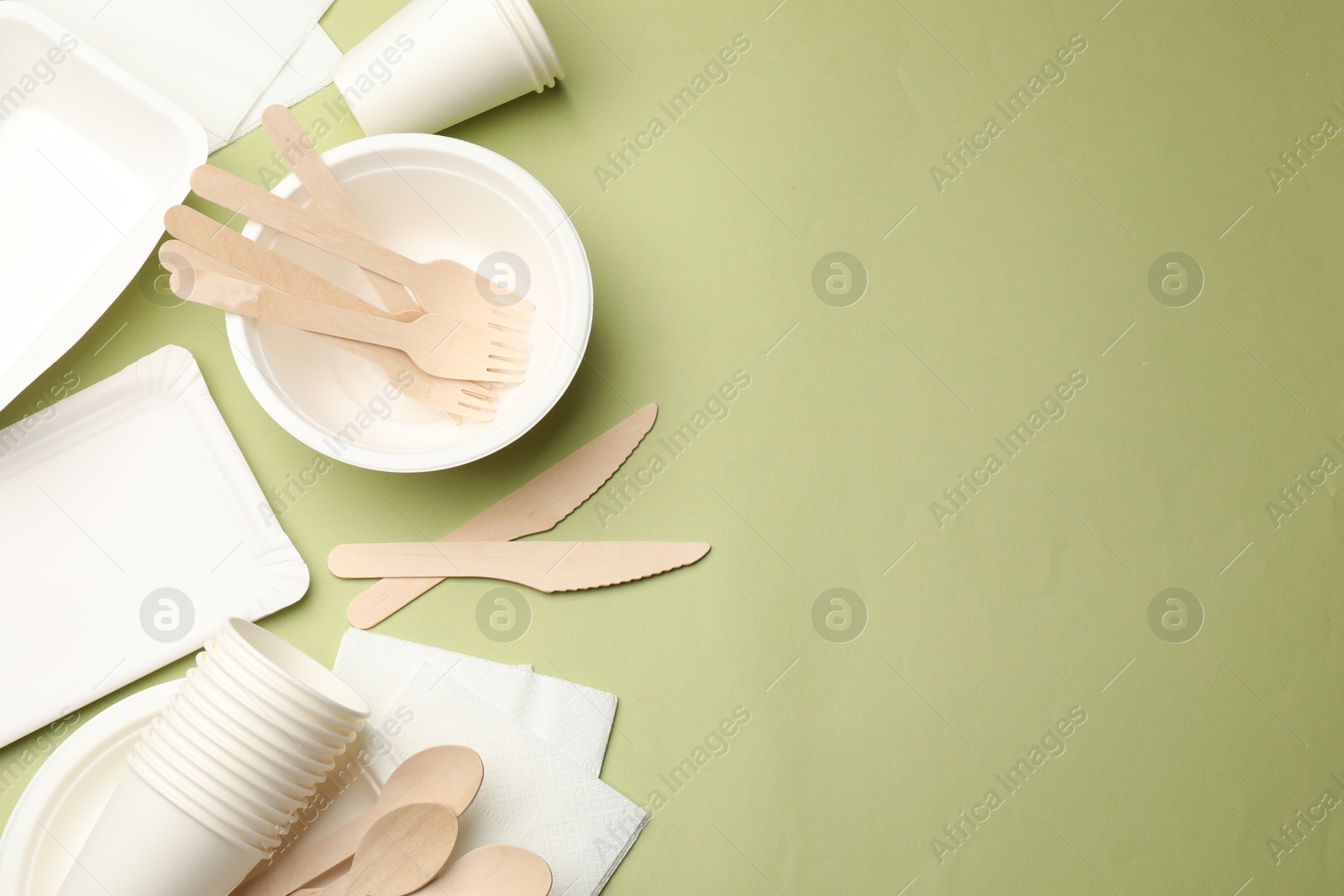 Photo of Set of disposable tableware on olive background, flat lay. Space for text