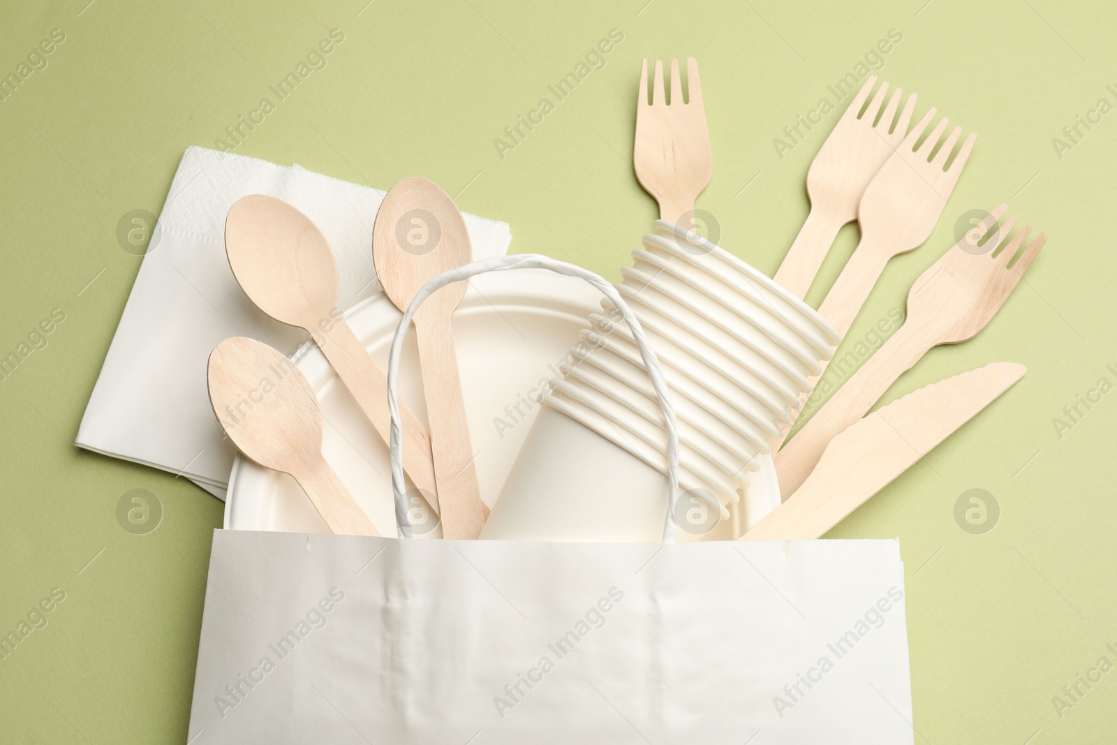 Photo of Set of disposable tableware on olive background, flat lay
