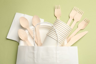 Photo of Set of disposable tableware on olive background, flat lay