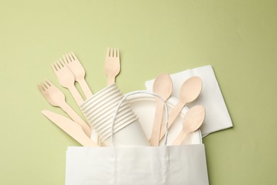 Photo of Set of disposable tableware on olive background, flat lay