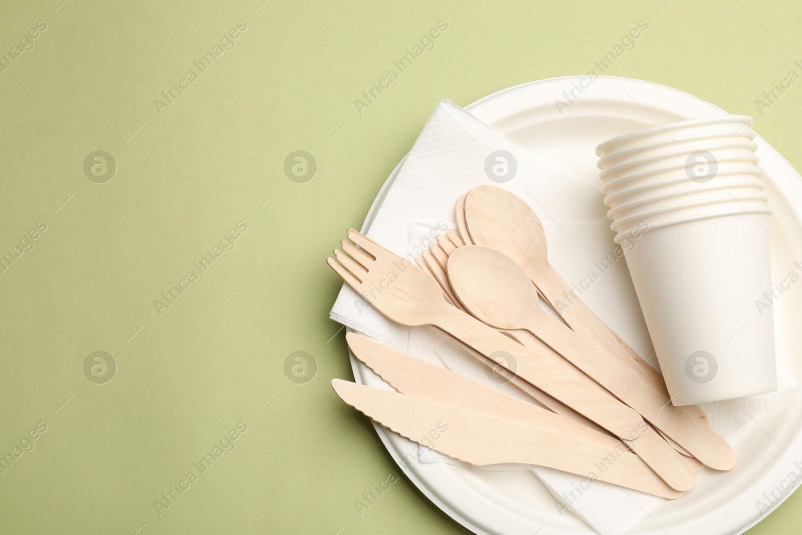 Photo of Set of disposable tableware on olive background, top view. Space for text