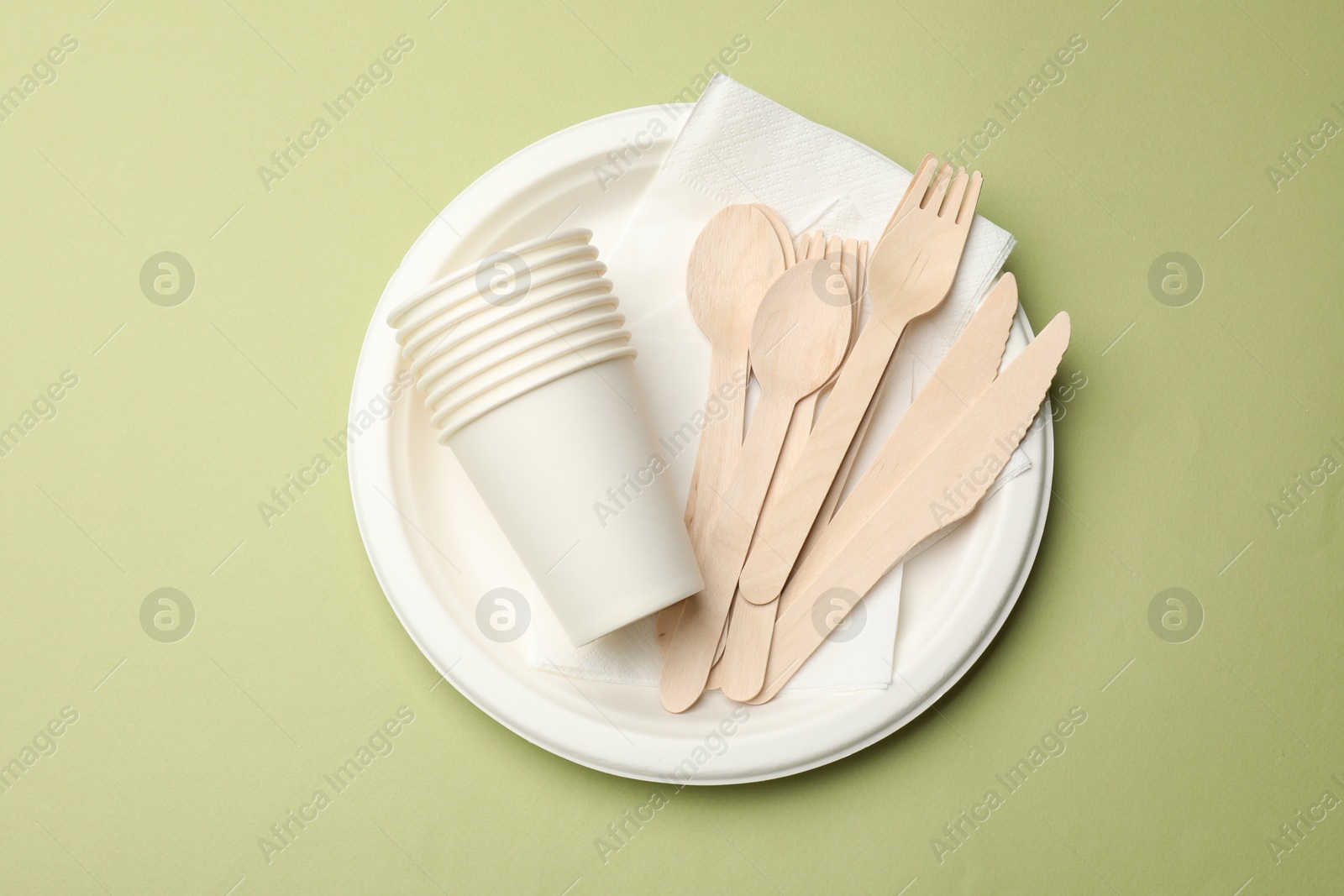 Photo of Set of disposable tableware on olive background, top view