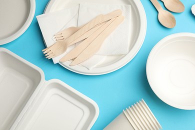 Photo of Set of disposable tableware on light blue background, flat lay