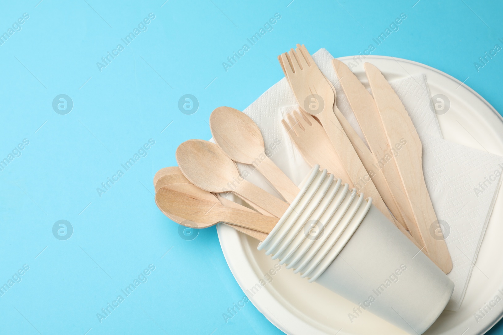 Photo of Set of disposable tableware on light blue background, top view. Space for text