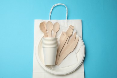 Photo of Set of disposable tableware on light blue background, top view
